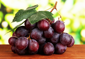 Ripe delicious grapes on table on bright background