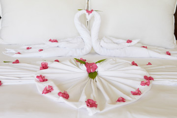 Obraz na płótnie Canvas Hotel Bedroom With Flowers Arranged On Sheets