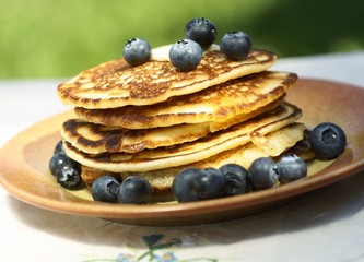 Stack of pancakes with blueberries on garden table