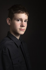 Portrait of a teenage boy against dark background