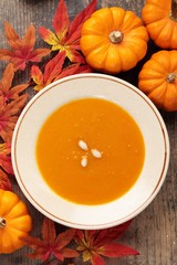 Plate with pumpkin soup and autumn decorations.