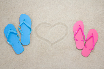 Fototapeta na wymiar blue, red flip flops and heart on beach