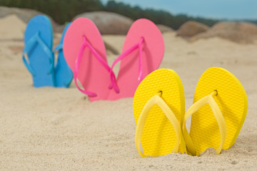 Fototapeta na wymiar colorful flip flops on white beach sand