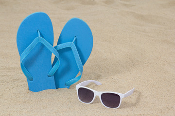 bright blue rubber flip flops and sunglasses on the sand
