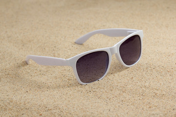 Fototapeta na wymiar białe modne okulary na piasku plaży
