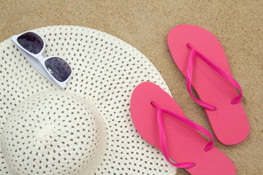 flip flops, sunglasses and hat on sandy beach