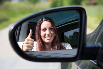 Autofahrerin zeigt Daumen hoch im Spiegel