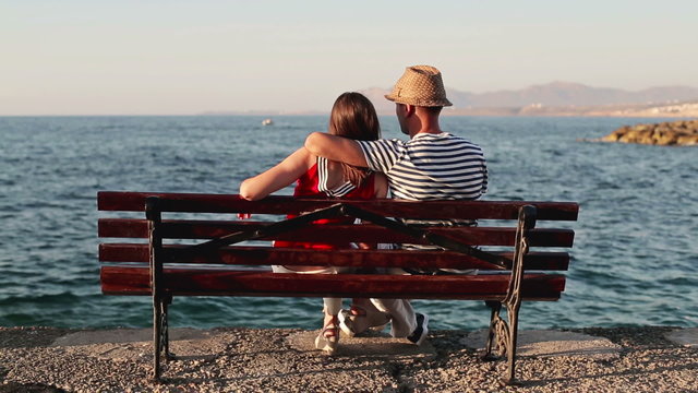 Couple in love sitting on bench by the sea