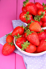 Fresh strawberry in bowl on pink wooden background
