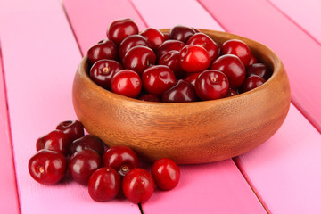 Cherry berries in bowl on wooden table close-up