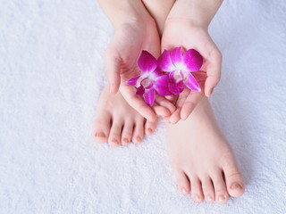 Young woman's hands, feet  and orchid flower