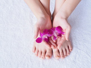 Young woman's hands, feet  and orchid flower