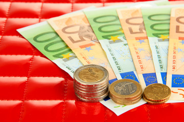 Euro banknotes and euro cents on red background