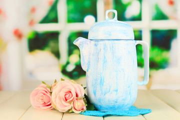 Antique white teapot on wooden table on window background
