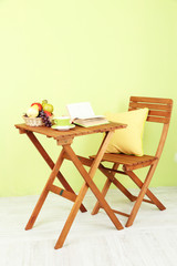 Wooden table with fruit,book and cup on it in room