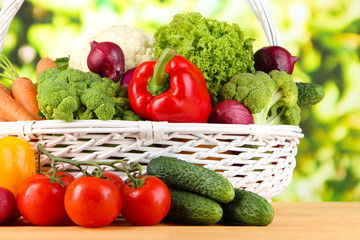 Fresh vegetables in white wicker basket on bright background