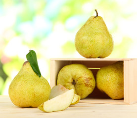 Pears in drawer on burlap on wooden table on nature background