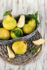 Pears in basket on braided tray on wooden table