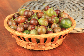 Fresh gooseberries in wicker basket on table close-up