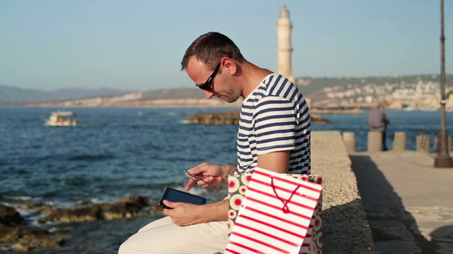 Man doing online shopping on tablet by the sea