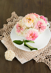 Roses in cup on napkins on wooden background