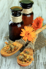 Medicine bottles and calendula flowers on wooden background