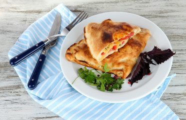 Pizza calzones on plate on napkin on wooden table