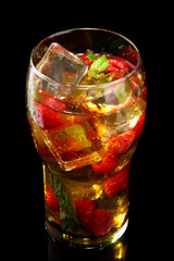 Iced tea with raspberries and mint on black background