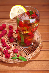 Iced tea with raspberries and mint on wooden table