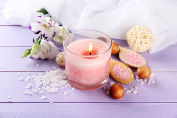 Beautiful pink candle with flowers on purple wooden background