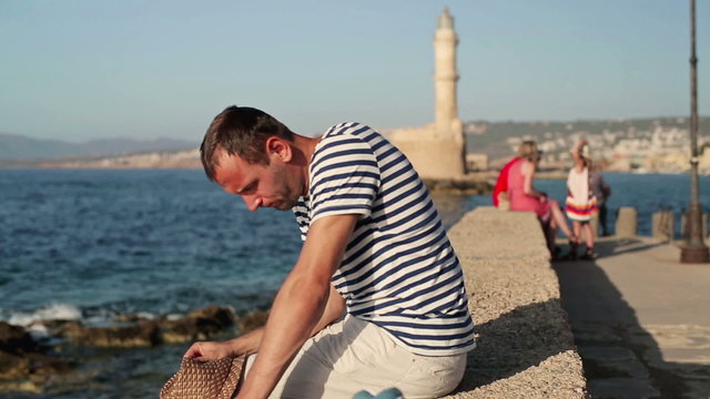 Sad young man sitting by the sea