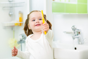 kid girl brushing teeth in bathroom