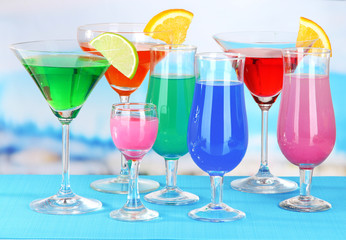 Glasses of cocktails on table near pool