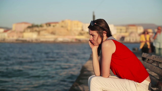 Sad, depressed woman sitting on bench by the sea