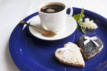 Two wedding cookies with a cup of coffee on the blue plate