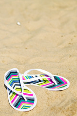 a pair of flip-flops on the sand of a beach