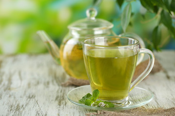 Teapot and cup of herbal tea with fresh mint flowers