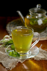 Cup and teapot of herbal tea with fresh mint flowers