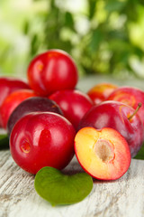 Ripe plums on wooden table on natural background