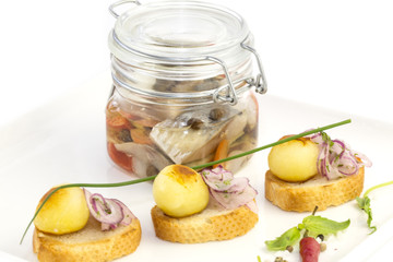 pickled herring in a glass jar with potato canapes