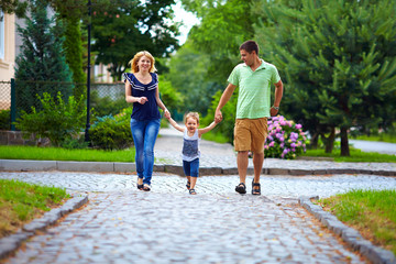 happy family of three persons running the street