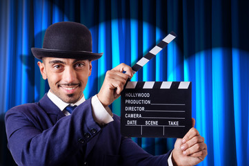 Man with movie clapper on curtain background