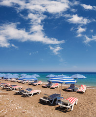 Fototapeta na wymiar Plaża z parasolami i krzesłami pod słońce i błękitne niebo
