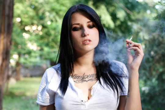 Beautiful young girl with a tattoo smokes