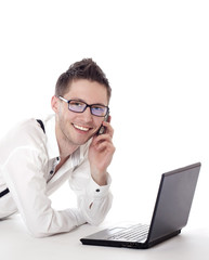 Male sitting in front of laptop and calling on mobile phone.