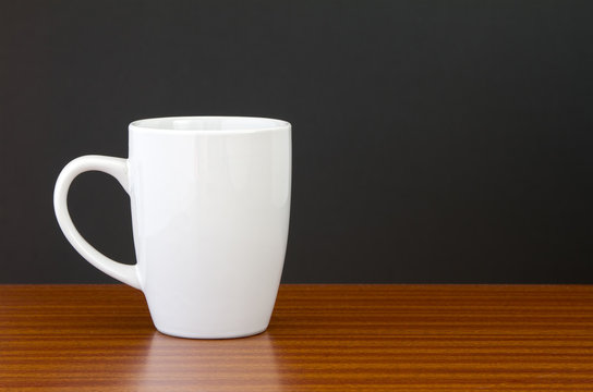 White Mug On Dark Wooden Table With Black Wall