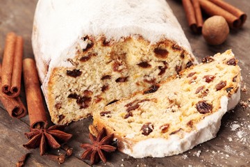 Christmas stollen and spices on wooden background.