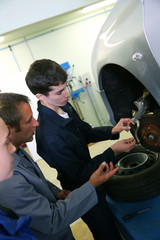 Instructor showing students how to repair car wheel