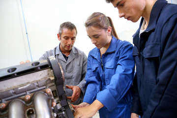 Students with instructor working on auto engine - obrazy, fototapety, plakaty