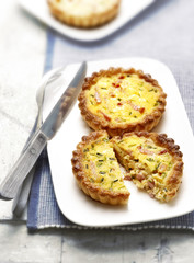 two quiches with bacon on a plate one cut in half